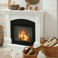 Przytulny kominek z palącym się ogniem. Czy palenie w kominku powoduje smog? W koszach drewno na opał.