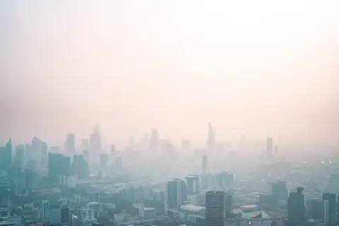 Widok miasta spowitego mgłą, która może być efektem różnych rodzajów smogu.