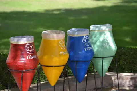 Kolorowe garnki do segregacji śmieci: czerwony na szkło, żółty na plastik, niebieski na papier, zielony na metal.