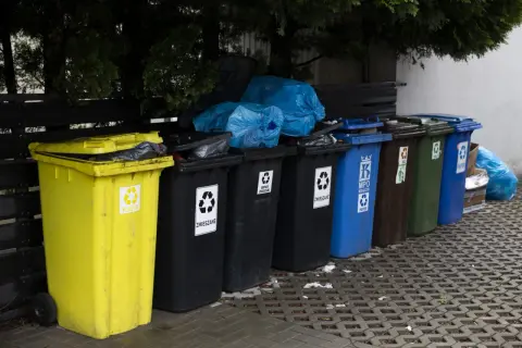 Różnokolorowe kosze na śmieci, w tym żółty na plastik, czarne na zmieszane, niebieski na papier. Zastanawiasz się, ile za śmieci w gminie?