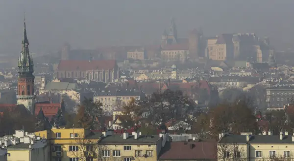 Mglisty widok Krakowa z wieżą kościelną i zamkiem. Warto wiedzieć, jak chronić się przed zanieczyszczeniami powietrza w takich warunkach.