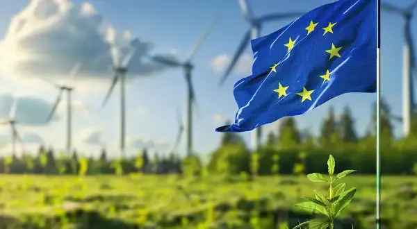 Flaga UE powiewa nad farmą wiatrową, symbolizując, czego dotyczy zielony ład: zrównoważony rozwój i czystą energię dla przyszłości.