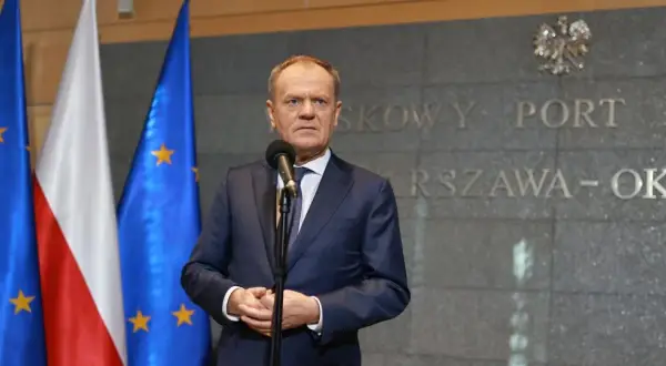 Premier Tusk, stojąc przed flagami Polski i UE, przemawia na tle napisu "Warszawa-Okęcie". Kto poparł zielony ład?