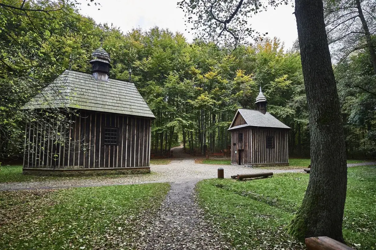 Dwie drewniane kapliczki w rezerwacie przyrody Las Łagiewnicki, otoczone jesiennym lasem.