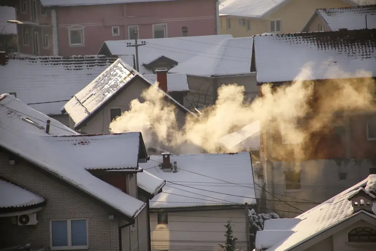 Zimowy krajobraz z dymem unoszącym się z kominów. Smog co możemy zrobić? Zastanówmy się nad czystym powietrzem.