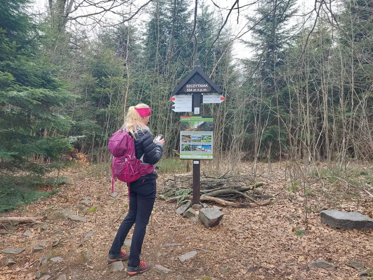 Turystka z plecakiem przy znaku szczytu Szczytniak (554 m n.p.m.) w rezerwacie przyrody.