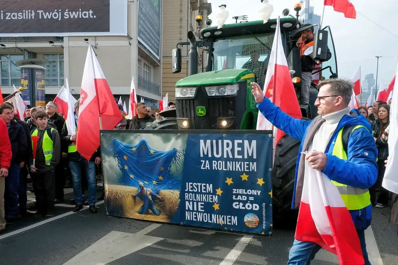 Rolnicy protestują przeciwko Zielonemu Ładowi, który ich zdaniem oznacza głód. Na transparencie widać rolnika klęczącego na polu pszenicy pod flagą UE.