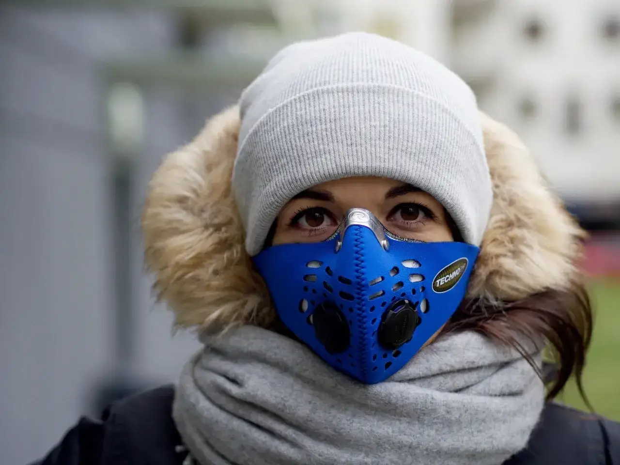 Twarz kobiety w masce antysmogowej i czapce. Zastanawia się, jaki smog dzisiaj w Warszawie.